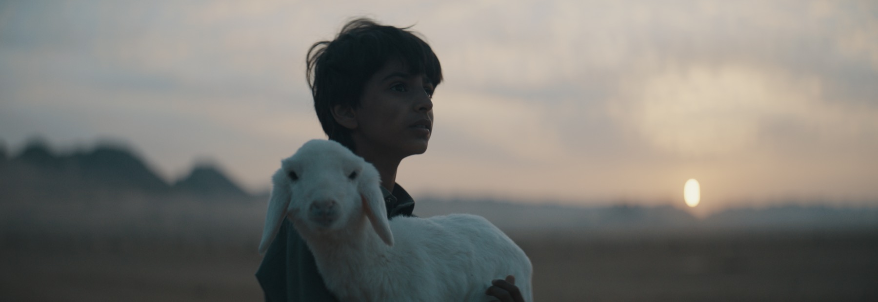 Abdulaziz Alqahtani holding the lamb at sunset in The Lamb