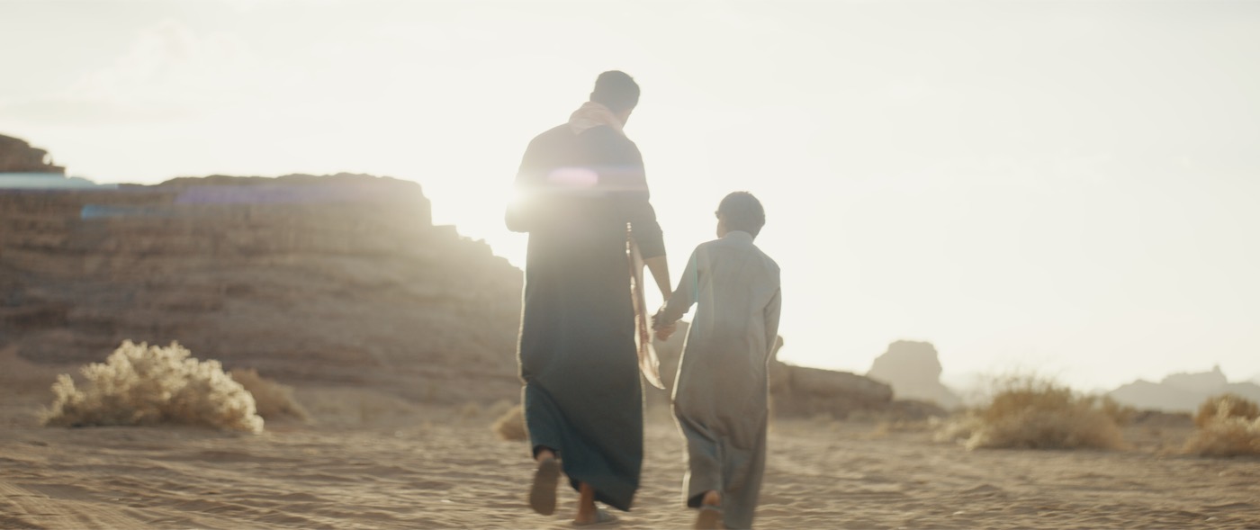 A father and son walking together through the desert in The Lamb