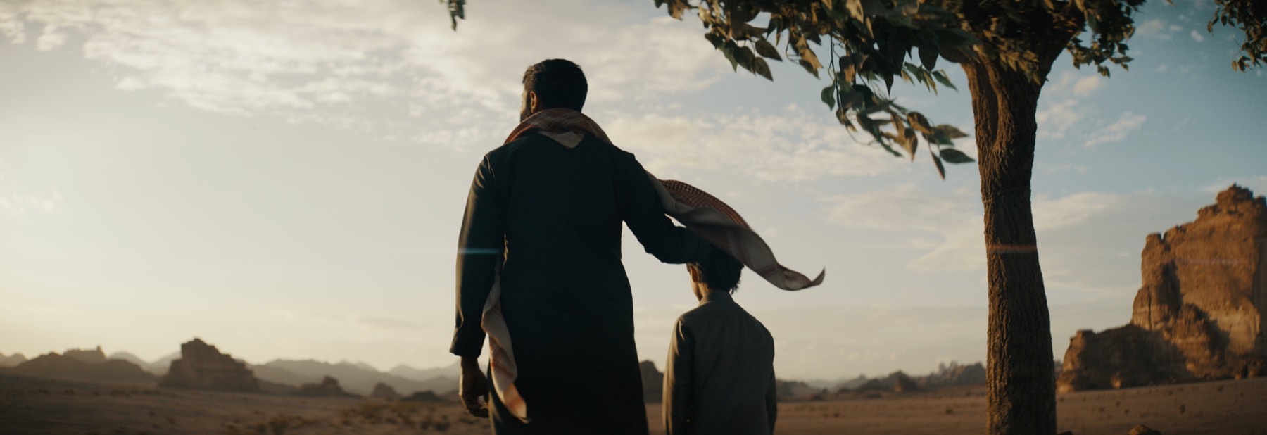 A father and son beneath a solitary tree in The Lamb