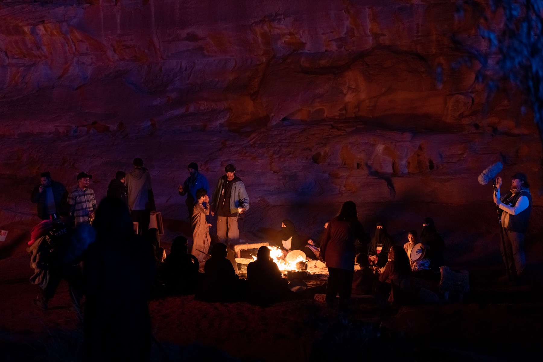 Cast and crew gathered around a campfire during a night shoot for The Lamb
